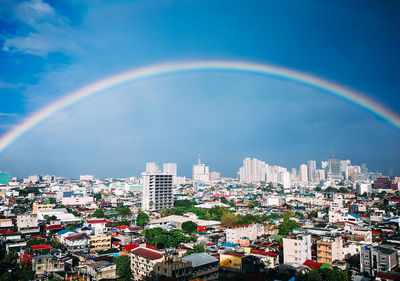 Rainbow over buildings in city against sky