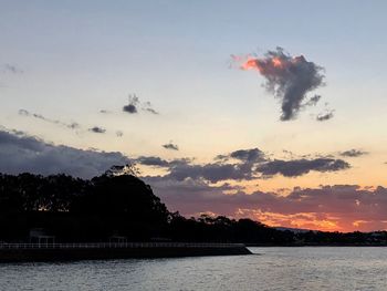 Silhouette trees by lake against sky during sunset