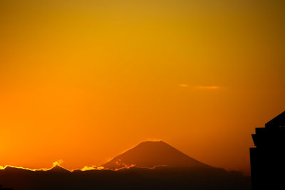 Scenic view of silhouette mountains against orange sky