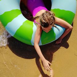 High angle view of girl lying on inflatable ring at beach