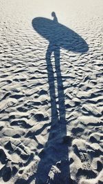 Shadow of woman with a surf walking on sand at beach