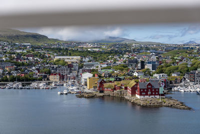 Aerial view of townscape by sea against sky