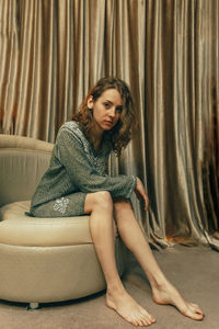 Portrait of young woman sitting on sofa at home