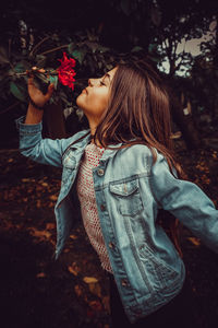 Girl smelling flower growing on plant at park