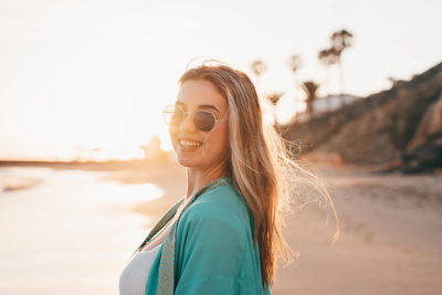 Portrait of young woman standing against sky