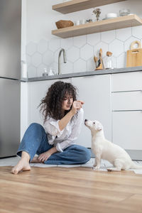 Full length of woman sitting on floor at home