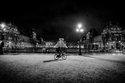 Man with bicycle on street at night