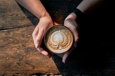 Midsection of woman holding coffee cup on table