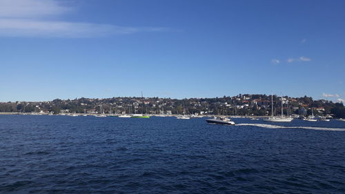 Scenic view of sea by buildings against blue sky