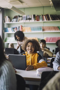 Smiling girl with laptop at desk in classroom