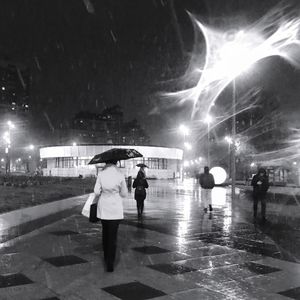 People walking on wet street at night