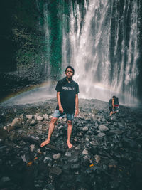 Full length of young man standing against rocks