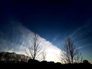 Low angle view of silhouette bare trees on field against sky