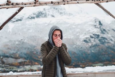 Young man feeling cold while standing against mountain