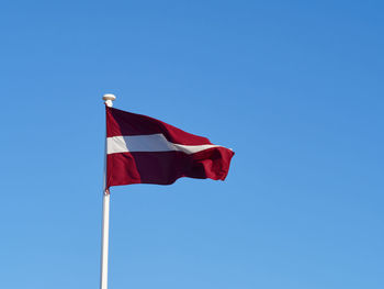 Low angle view of flag against clear blue sky