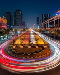 Light trails on road amidst buildings in city at night