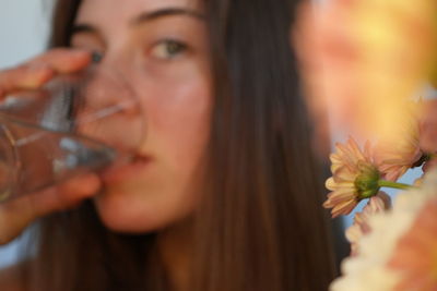 Close-up portrait of a beautiful young woman drinking glass