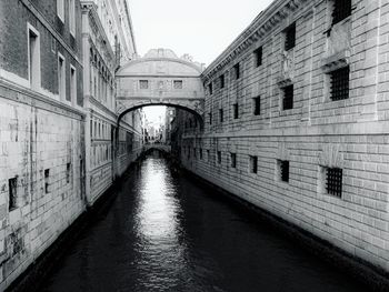 Bridge over canal amidst buildings against sky