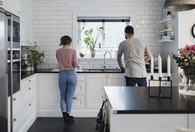 Rear view of couple working in kitchen at home