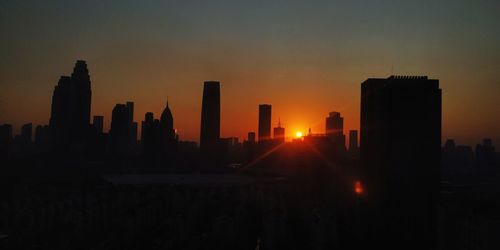 Silhouette buildings against sky during sunset in city