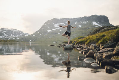 Woman doing yoga at lake in mountains