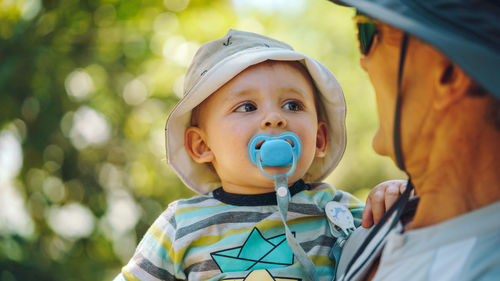 Close-up of baby boy with pacifier in mouth being carried by father