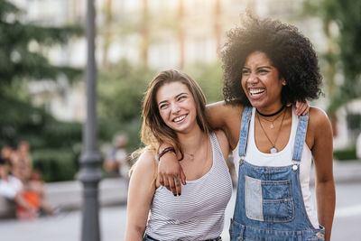 Happy female friends standing in city