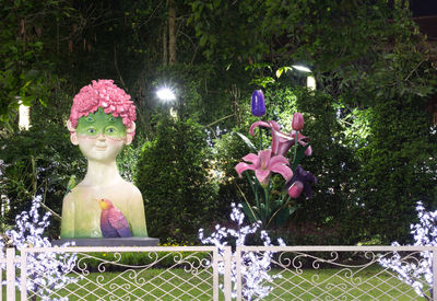 Close-up of pink statue by flower trees in park