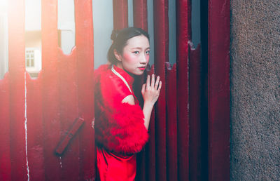 Portrait of beautiful young woman standing by metal gate