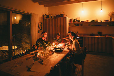 Happy family enjoying candle night dinner while sitting at dining table in home