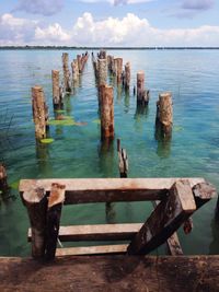 Wooden posts on pier over sea against sky