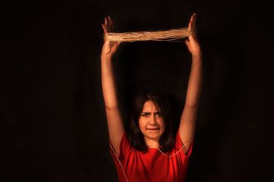 Portrait of woman with string against black background