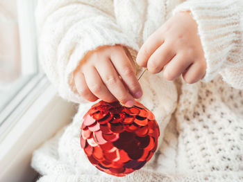 Kid with red decorative ball for christmas tree. cozy outfit for snuggle weather. new year.