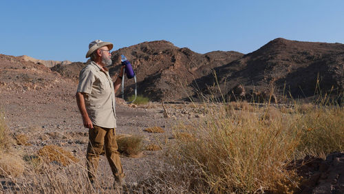 Senior man drinking water in the desert 