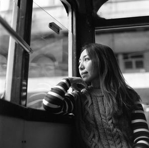 Young woman looking through window in bus