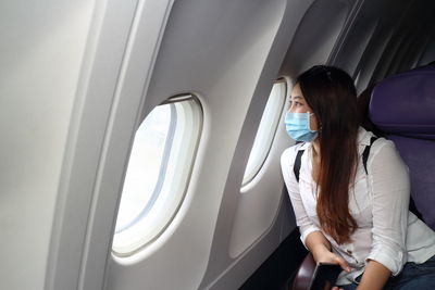 Woman looking through window in airplane