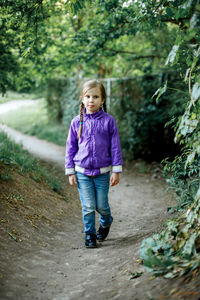 Portrait of girl walking by trees