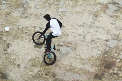 Man performing stunt with bicycle on footpath