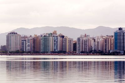 Reflection of buildings in lake against sky in city