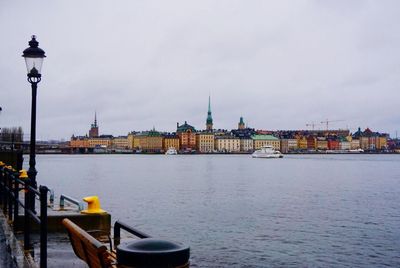 Boat moving on lake in city against sky