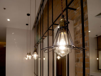 Low angle view of illuminated pendant light hanging from ceiling