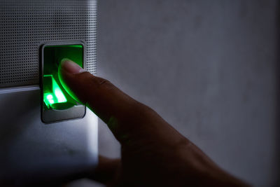 Close-up of person holding mobile phone against wall