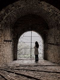 Rear view of woman standing against old building