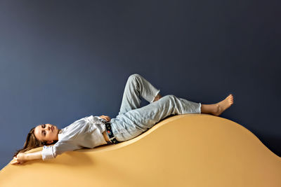 Portrait of a young woman lying on a geometric sand-colored couch.abstract.