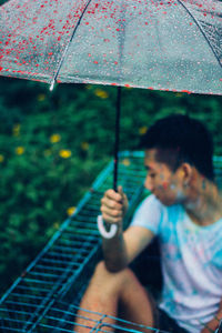 Man in metallic structure holding umbrella during rainy season