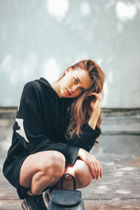 Portrait of beautiful young woman crouching outdoors