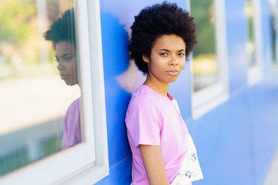 Portrait of young woman looking through window