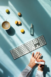 Cup of coffee and macaroons in sunlight and women hands holding a sanitizer.