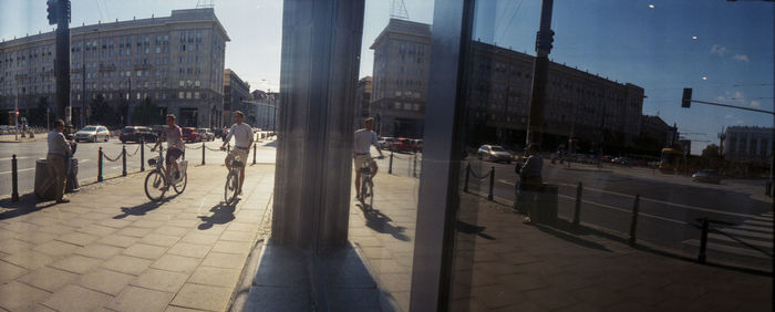 People walking on sidewalk by buildings in city