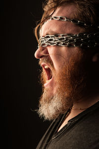 Close-up portrait of man wearing hat against black background